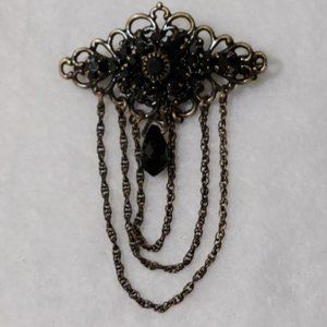 gold toned brooch with black beads and hanging chain.